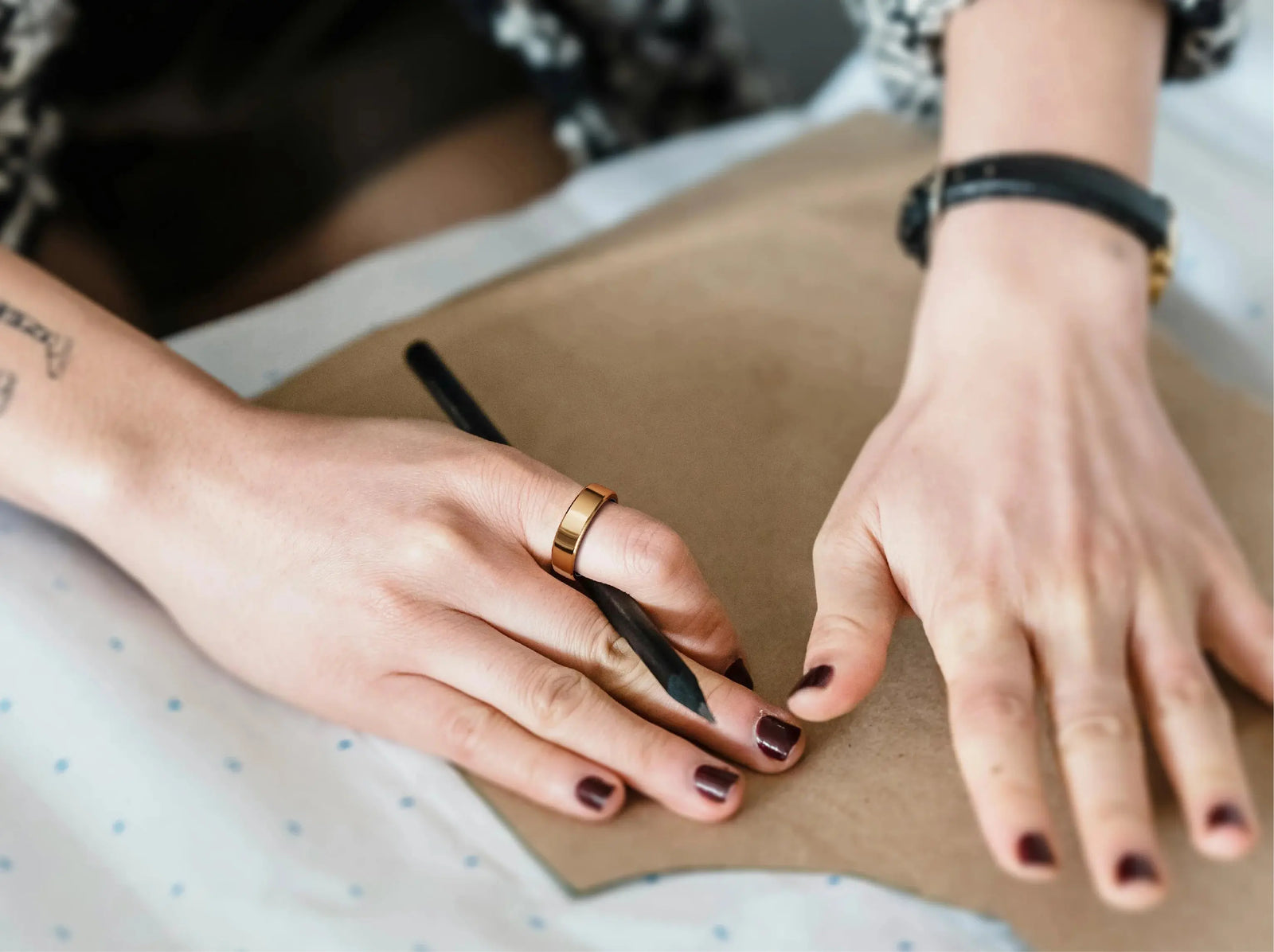 Reference marketing photo of a gold RingConn smart ring worn while sketching